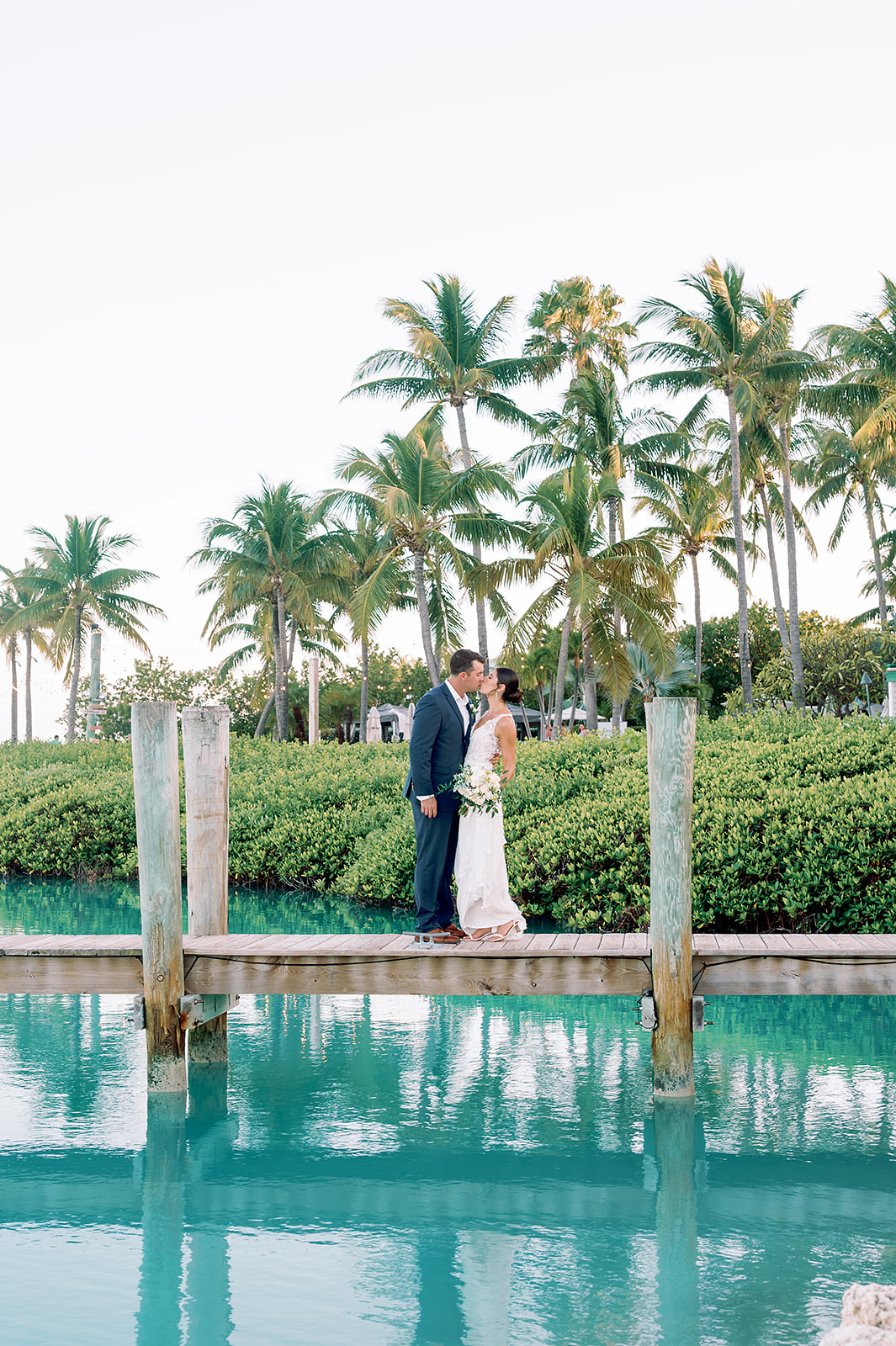 Florida Keys photographer photographs Hawks Cay wedding with bride and groom kissing on a dock in the water