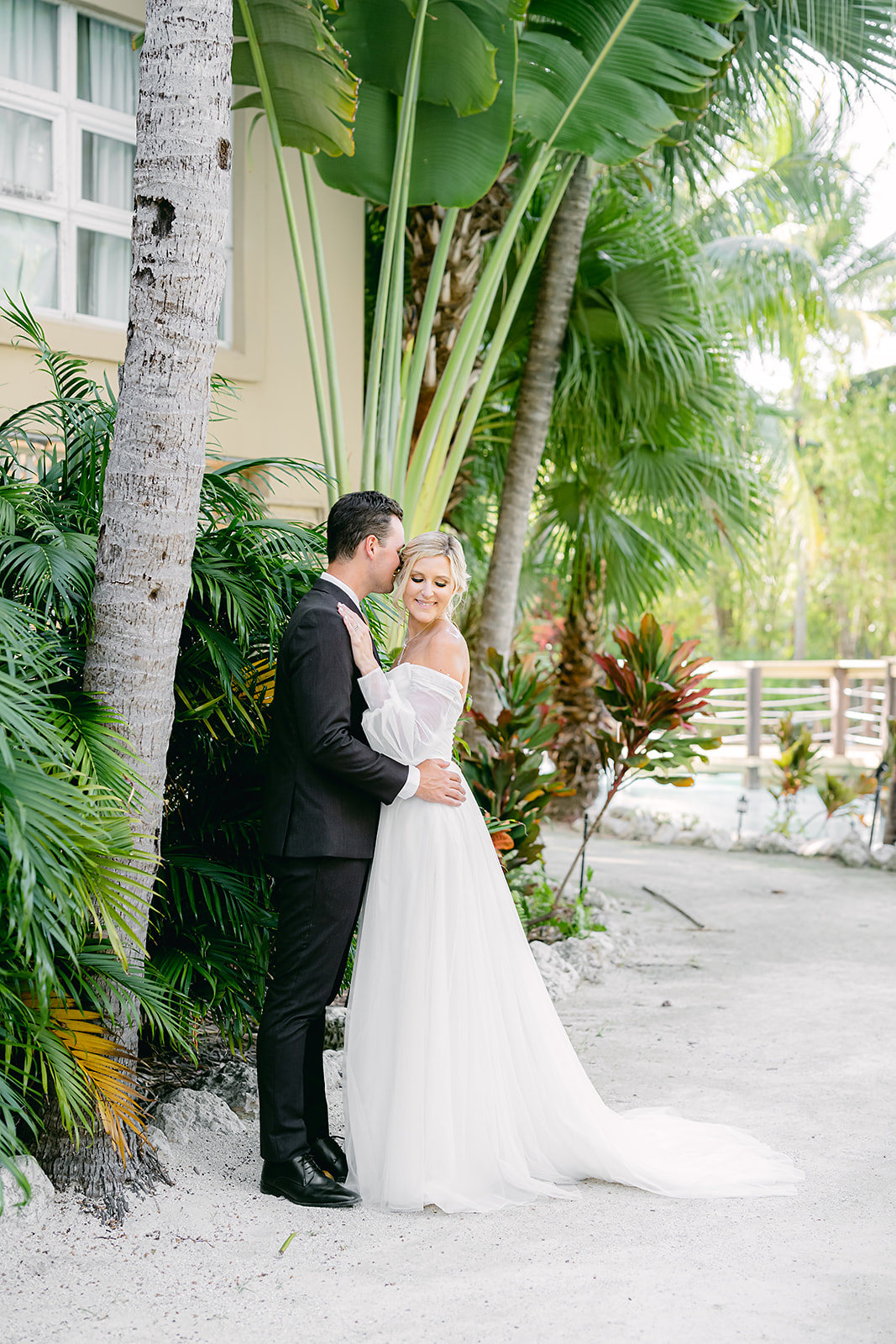 bride and groom holding each other under palm trees at beach resort in Key West
